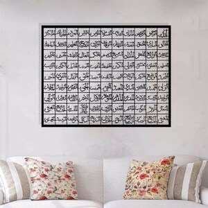 May include: Black and white calligraphy art print with Arabic script in a grid pattern. The print is framed in a black frame and is hanging on a white wall.