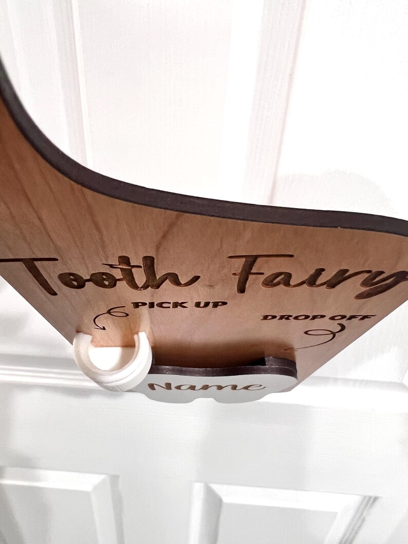 May include: Wooden tooth fairy box with a white plastic tooth holder. The box has the words "Tooth Fairy" and "Pick Up" and "Drop Off" written on it. There is a space for a name on the box.