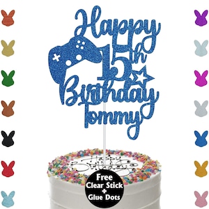 May include: A blue glitter cake topper with the words "Happy 15th Birthday Tommy" and a controller design. The cake topper is on a white cake with colorful sprinkles. Includes a clear stick and glue dots.