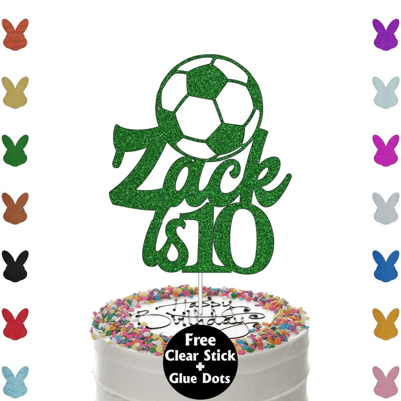 K&ouml;nnte beinhalten: Gr&uuml;ner Glitzer-Kuchenaufsatz mit Fu&szlig;ball-Design und dem Namen "Zack is 10". Der Aufsatz befindet sich auf einem wei&szlig; glasierten Kuchen mit bunten Streuseln und dem Schriftzug "Happy Birthday".
