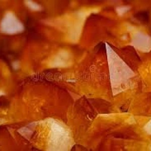 Puede incluir: Primer plano de un grupo de cristales de citrino naranja. Los cristales son facetados y tienen una apariencia translúcida y vidriosa.