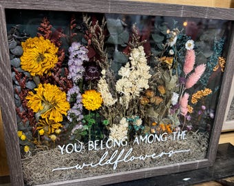 May include: A framed pressed flower arrangement with a white background and the text "You belong among the wildflowers".