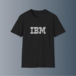 May include: A white ceramic mug with a black handle and the text "But First, Coffee" in a bold, black font. The mug is set against a blurred background, suggesting a cozy setting.