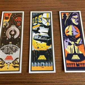 May include: Three Star Wars movie poster prints featuring scenes from the original trilogy. The first print features Darth Vader and the Death Star. The second print features a scene from the Battle of Hoth. The third print features a scene from the Battle of Endor.