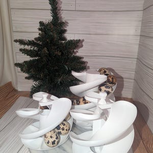 May include: White plastic egg holder with a spiral design. The holder is filled with quail eggs. The holder is on a marble surface.
