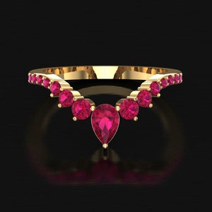 May include: A gold ring with a curved design, set with a series of round, bright pink gemstones and a single pear-shaped pink gemstone at the centre. The ring is displayed against a dark background, emphasising its elegant design.