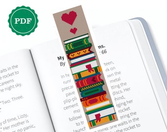 May include: A cross-stitch pattern for a bookmark featuring a stack of colourful books with a red heart on top. The text "My" and "By" are stitched below the books.