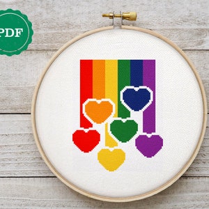 May include: A rainbow cross stitch pattern with a row of colorful hearts hanging from the bottom. The rainbow is made up of red, orange, yellow, green, blue, indigo, and violet. The hearts are red, orange, yellow, green, blue, and purple.