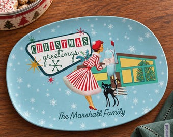 May include: An oval light blue serving platter featuring a mid-century illustration of a person in a red and white striped dress, a black cat, and a house with a Christmas tree. The text reads Christmas greetings and The Marshall Family.