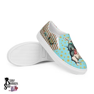 May include: White slip-on canvas shoes with a blue and gold pattern featuring a white rabbit wearing a waistcoat and holding a pocket watch. The pattern also includes a crown and other details.