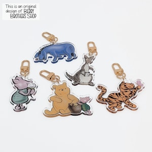 May include: Five acrylic keychains featuring cartoon characters including a blue donkey, a pink piglet holding a flower, a yellow bear with a honey pot, a kangaroo with a joey, and a striped tiger with a butterfly. Text reads: This is an original design of BERRY BROTHERS SHOP.