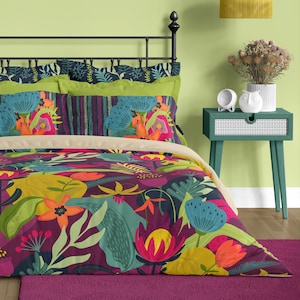 May include: A bed with a vibrant floral duvet cover and pillowcases. The bedding features a colorful design with large flowers in shades of pink, orange, yellow, and blue against a dark purple background. The headboard is black, and the room has a green wall.
