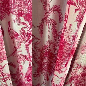 Peut inclure: Un rideau en tissu présentant un motif toile de jouy rose vif imprimé sur un fond blanc. Le design affiche des illustrations détaillées de palmiers tropicaux, d'oiseaux exotiques et de tigres disposés dans un motif scénique répétitif.