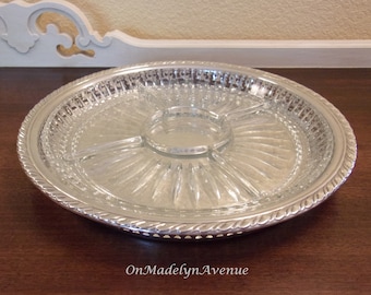 May include: A round serving tray featuring a clear glass insert with a central circular compartment and four radiating sections. The glass is encased in a silver-toned metal frame with a decorative twisted rope edge and a pierced lattice border.