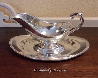 May include: A polished silver-toned gravy boat with a curved handle and a matching oval underplate. The metal surface is highly reflective, showing light and surroundings. The text OnMadelynAvenue is printed in white at the bottom of the image.