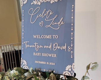May include: A blue and white baby shower sign with the text "Welcome to Tonantzin and David's Baby Shower December 16, 2024".