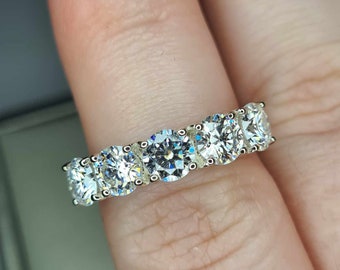 Puede incluir: Un anillo de banda de plata con cinco piedras redondas y transparentes engastadas en una fila.