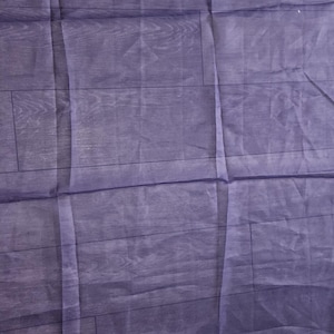 May include: A purple sheer fabric backdrop with a wood grain pattern. The fabric is wrinkled and has a slight sheen.
