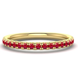 May include: A thin gold band with a row of small red gemstones.