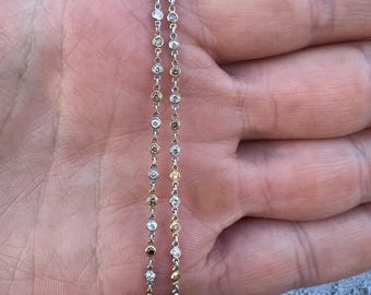 May include: A delicate gold and silver chain necklace with small round diamonds. The chain is made of two strands of metal, one gold and one silver, with diamonds set in each strand.