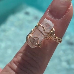 May include: A gold wire wrapped ring featuring a clear quartz crystal.