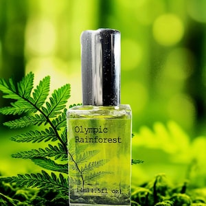 May include: A small glass bottle with a silver cap, filled with a clear liquid. The bottle is labeled "Olympic Rainforest" and "14ml (0.5 fl oz)". The bottle is sitting on a bed of green moss.