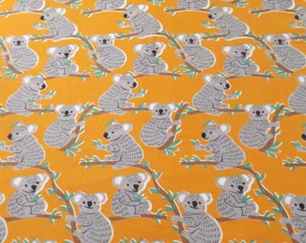 May include: A yellow fabric with a repeating pattern of gray koalas sitting on branches with green leaves. The koalas are all facing the same direction and have a simple, cartoon-like design.