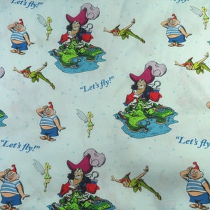 May include: A blue and white fabric with a repeating pattern of Captain Hook, Peter Pan, and Tinkerbell. The fabric features the text "Let's fly!" repeated throughout the pattern.