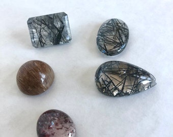 An assortment of black, red and gold rutilated quarts in different shapes and sizes.
