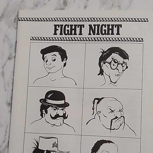 Peut inclure: Illustration en noir et blanc de la jaquette d'un jeu vidéo intitulé Fight Night, un jeu pour Commodore 64/128. La jaquette présente quatre personnages de dessin animé avec différentes expressions faciales et coiffures. Le texte "Fight Night" est en gras en haut de la boîte. Le texte "For Commodore 64/128" est en bas de la boîte. Le texte "Accolade" est en grande police en bas de la boîte.