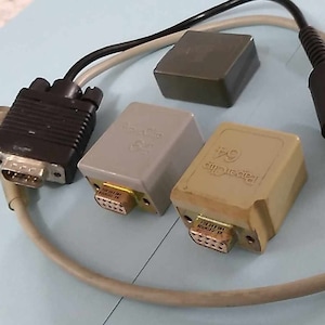 Può includere: Primo piano di un set di componenti elettronici, tra cui una scatola grigia con la scritta "remarkable" stampata su di essa, una scatola grigia con la scritta "remarkable" stampata su di essa, un connettore nero con un cavo grigio e un cavo grigio con un connettore nero.