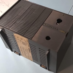 May include: A black metal box with a label that says "ADMIRAL" and a series of small holes on the top and sides. The box has a keyhole on the top.