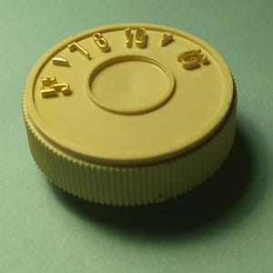 Peut inclure: Un bouchon de bouteille en plastique blanc avec les chiffres dorés 17, 18, 19 et 20 imprimés autour du bord.