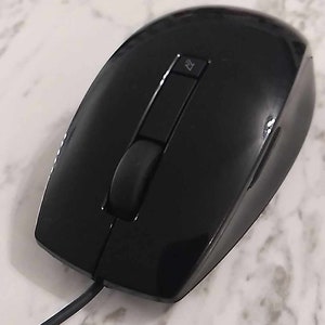 Puede incluir: Un ratón de ordenador negro con cable, con un solo botón y una rueda de desplazamiento.