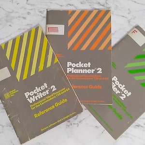 May include: Three grey paperback books with yellow, orange, and green striped covers. The books are titled "Pocket Writer 2", "Pocket Planner 2", and "Pocket Writer 2".