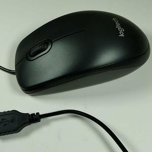 Könnte beinhalten: Schwarze Logitech Computermaus mit Scrollrad und USB-Anschluss. Die Maus hat ein glattes, ergonomisches Design und ein schwarzes Kabel. Das Logitech-Logo ist oben auf der Maus sichtbar.