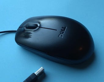 Könnte beinhalten: Schwarze Dell Computermaus mit Scrollrad und kabelgebundenem USB-Anschluss. Das Dell-Logo ist auf der Maus sichtbar. Die Maus befindet sich auf einer blauen Oberfläche.