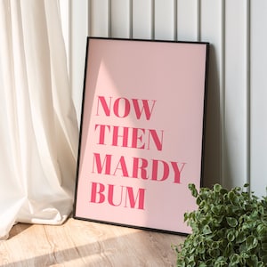 May include: A pink framed poster with the text "NOW THEN MARDY BUM" in bold, pink letters.