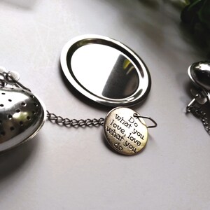 May include: Silver heart-shaped tea infuser with a chain and a round silver disc. The infuser has a small tag attached to it that reads "Do what you love, love what you do."