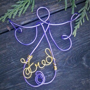 Peut inclure: Ornement d'ange en fil de fer violet avec le mot "freed" écrit en fil de fer doré.