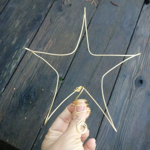May include: A gold wire star-shaped ornament with a spiral wire ring attached to the centre.