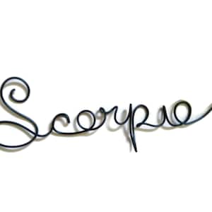 May include: Black wire sculpture of the word "Scorpio" in a cursive font.