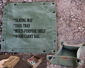 Könnte beinhalten: Eine quadratische olivgrüne Canvas-Matte mit Metallösen und Druckknöpfen an den Rändern. Der Text lautet: *SEATING MAT *TOOL TRAY *MULTI-PURPOSE SHELF *WOOD CARRY BAG. Eine kleinere, zu einer Schale gefaltete Version zeigt ein FAY DESIGN Lederetikett.