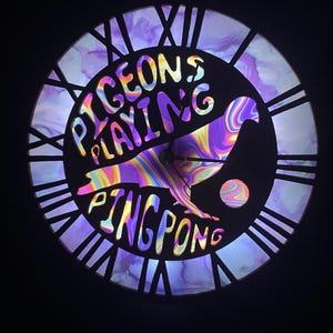 Reloj iluminado con palomas jugando al ping-pong
