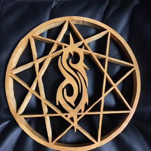 May include: A wooden wall decor featuring a stylized "S" symbol inside a circular eight-pointed star design.