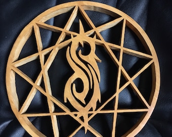 Könnte beinhalten: Eine Holz-Wanddekoration mit einem stilisierten "S"-Symbol in einem kreisförmigen achtzackigen Stern.