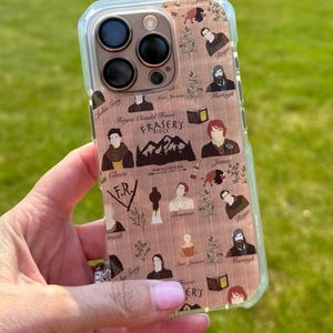 May include: A clear phone case featuring a wooden-look design with character illustrations and the text "FRASER'S RIDGE". The case has a clear border and is held in a hand against a green background.