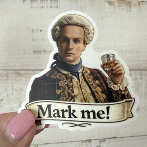 May include: A sticker featuring a portrait of a man in historical attire, holding a glass of amber liquid. The sticker has the text "Mark me!" on a banner below the portrait. The man is wearing a wig and a decorative jacket.