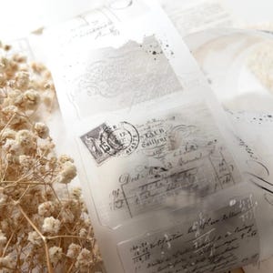 May include: Translucent decorative paper with vintage-style designs. The paper features faded black text, postage stamps, and ornate patterns. The overall aesthetic is a soft, neutral color palette, perfect for scrapbooking or crafting projects.