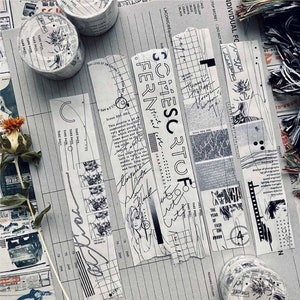 May include: Washi tape rolls and strips with a collage design. The tape features black and white graphics, including text, sketches, and floral patterns. The strips have torn edges and various text elements.